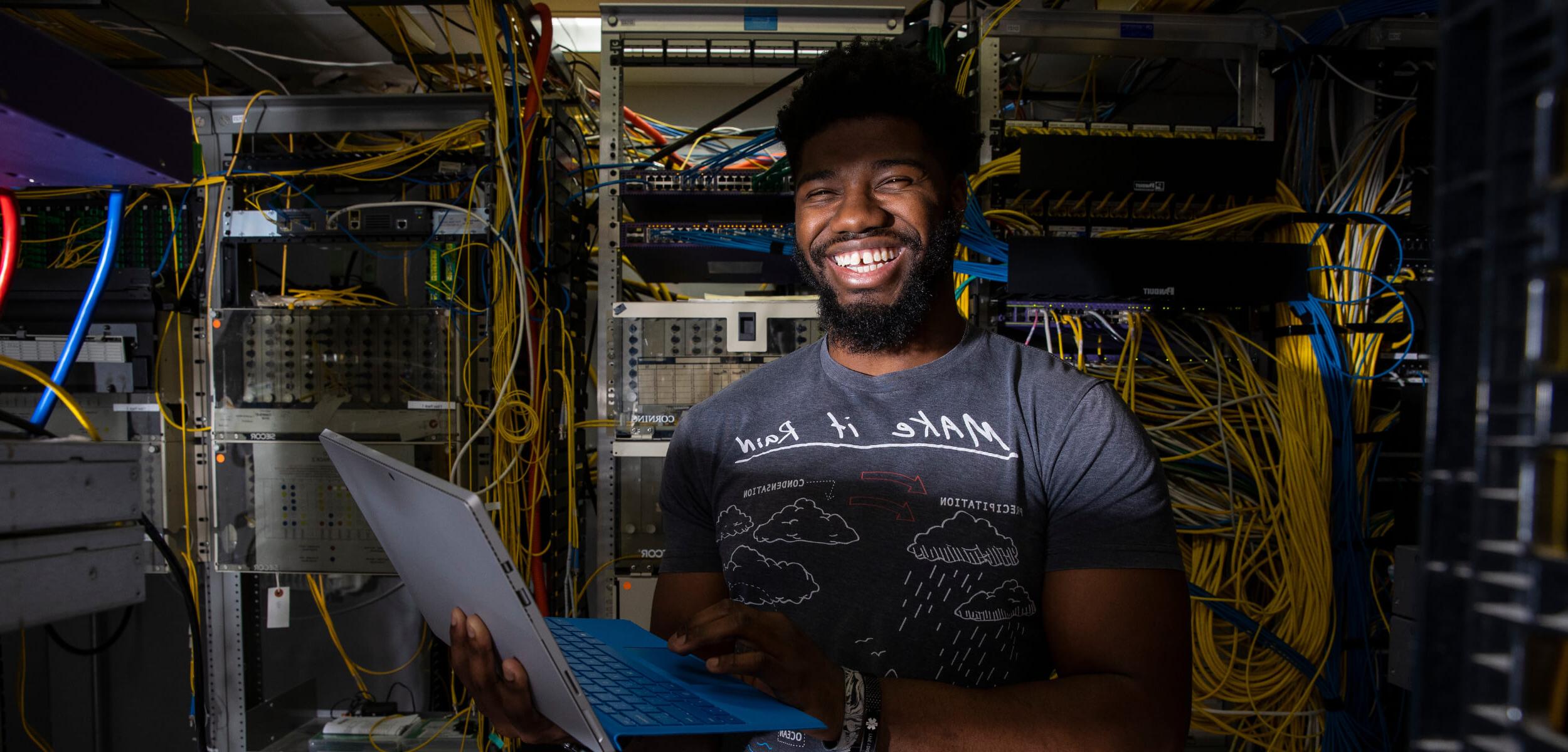 Student standing in server room smiling.