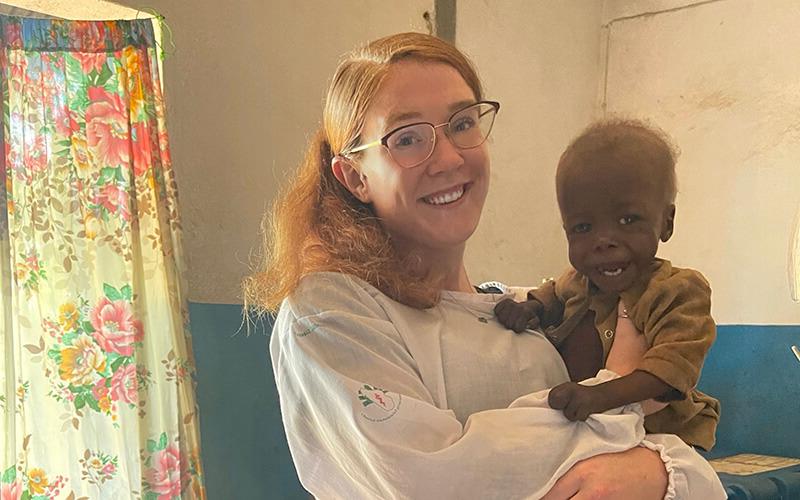 在线博彩 alumna and 和平队 volunteer Mackenzie Hafer with a child in a 马达加斯加 health clinic