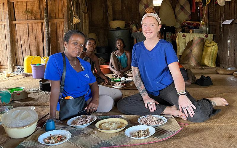 在线博彩 alumna and 和平队 volunteer Mackenzie Hafer with a family at mealtime in 马达加斯加