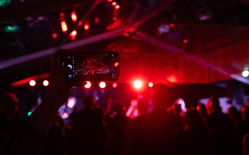 一位司仪拿着手机拍摄在线博彩总统黑领结晚会上的庆祝活动