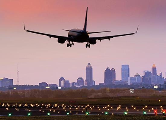 Plane landing on a runway with skyline in background