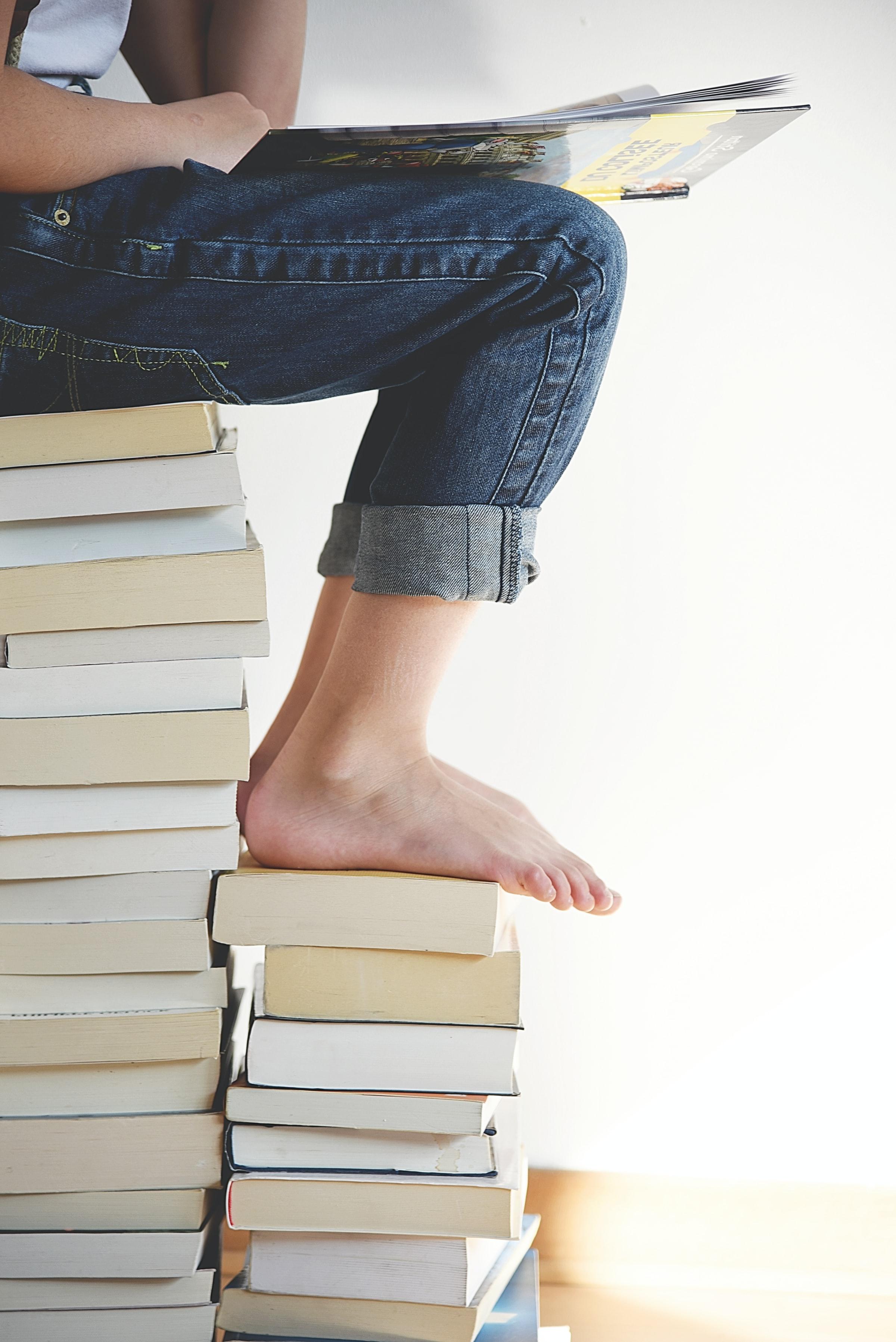 Person sitting on a pile of books